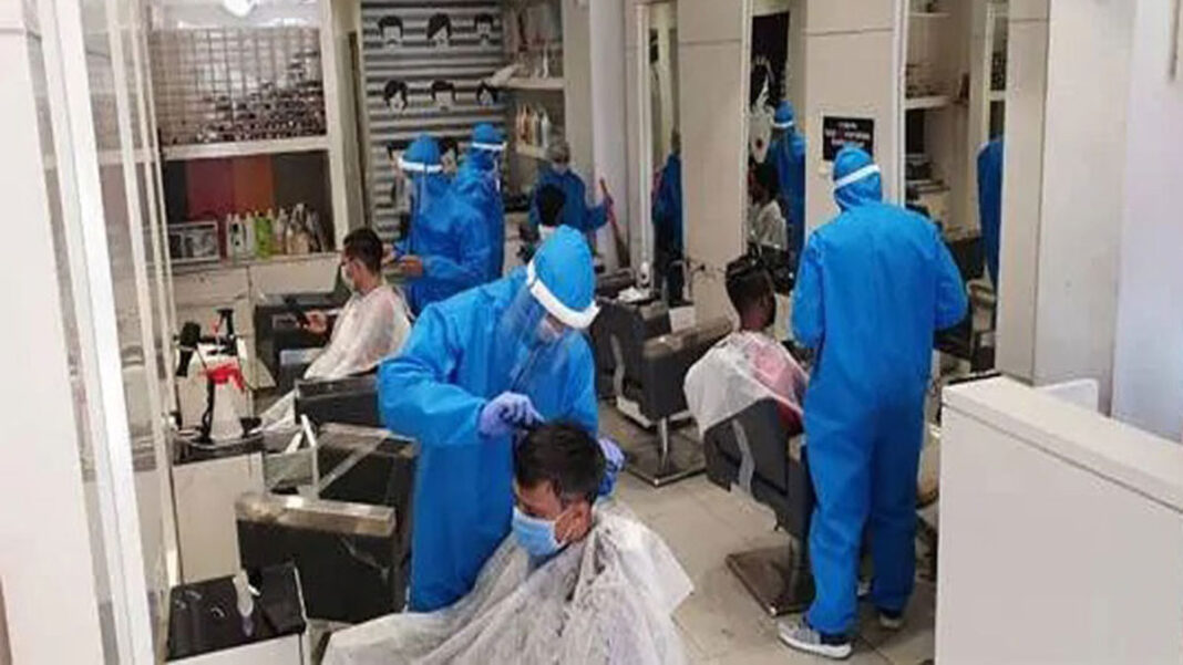 कोरोना संक्रमण से बचने के लिए सैलून कर्मचारी PPE Kit पहन काट रहे हैं बाल
